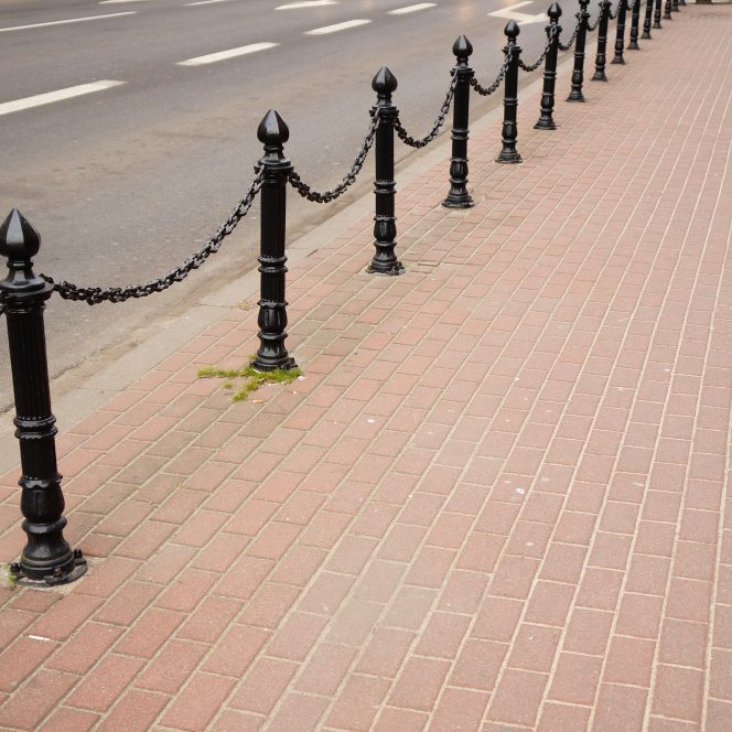 Black bollards with chain along a paved pavement