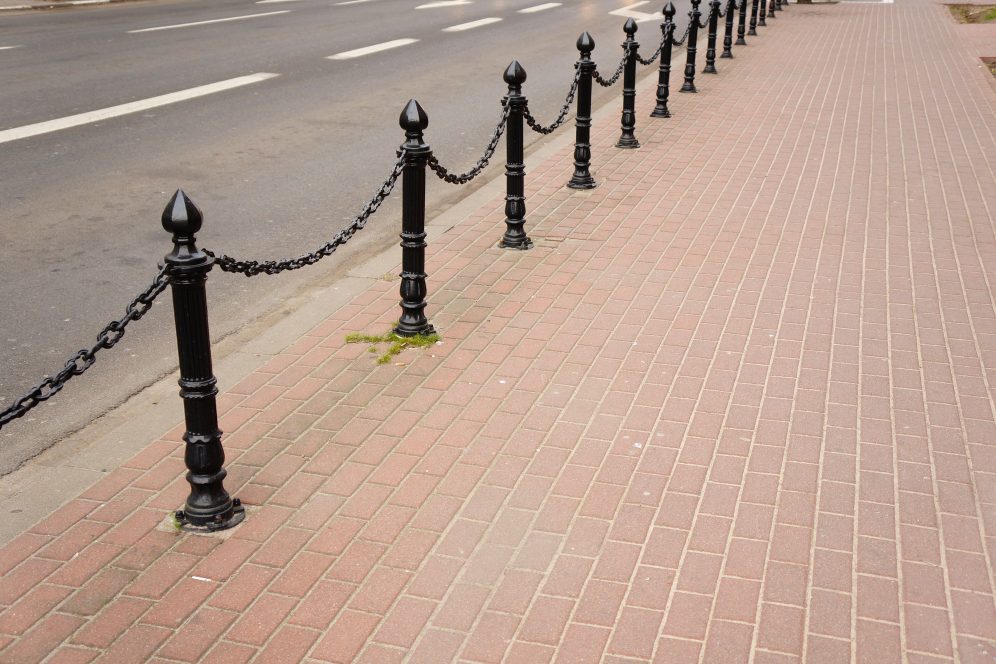 Black bollards with chain along a paved pavement