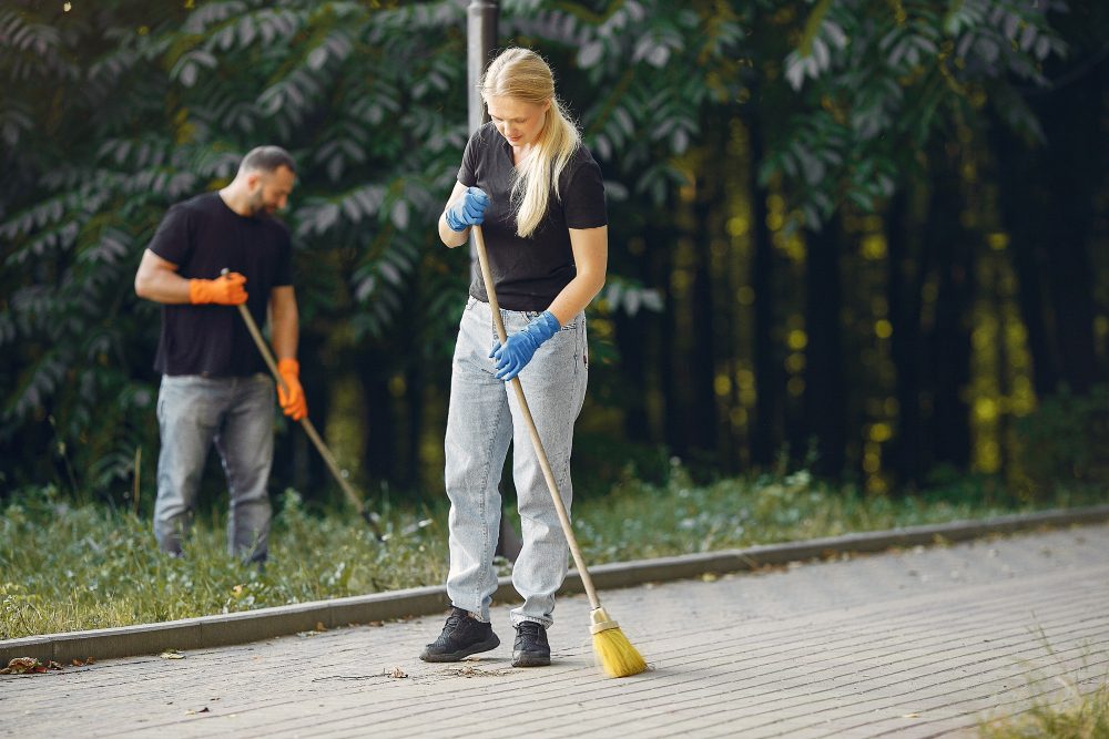 Two workers sweeping a paved area